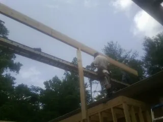 Carpenter setting a ridge beam over a new addition frame — Ice Dam Removal by Roofing Brothers in Peyton