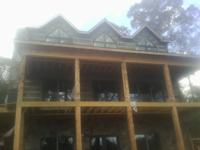 Dormers and porch framing on a large log home under construction — Roof Coating work by our crew in Peyton