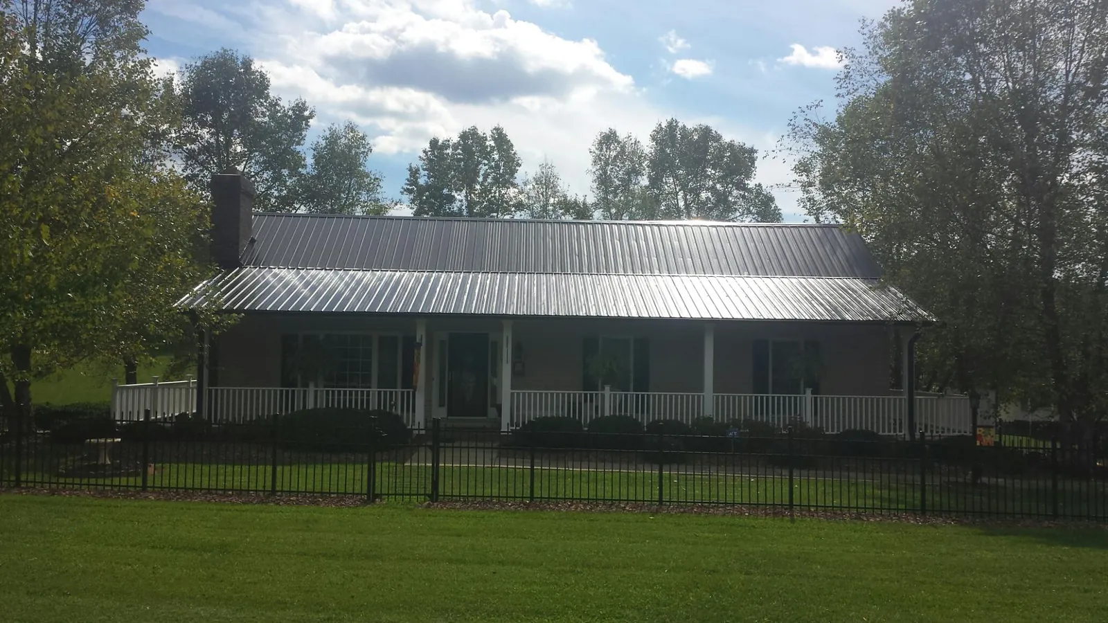 Gray metal roof on a brick ranch with a full width front porch — Gutter Guard Installation work by our crew in Peyton